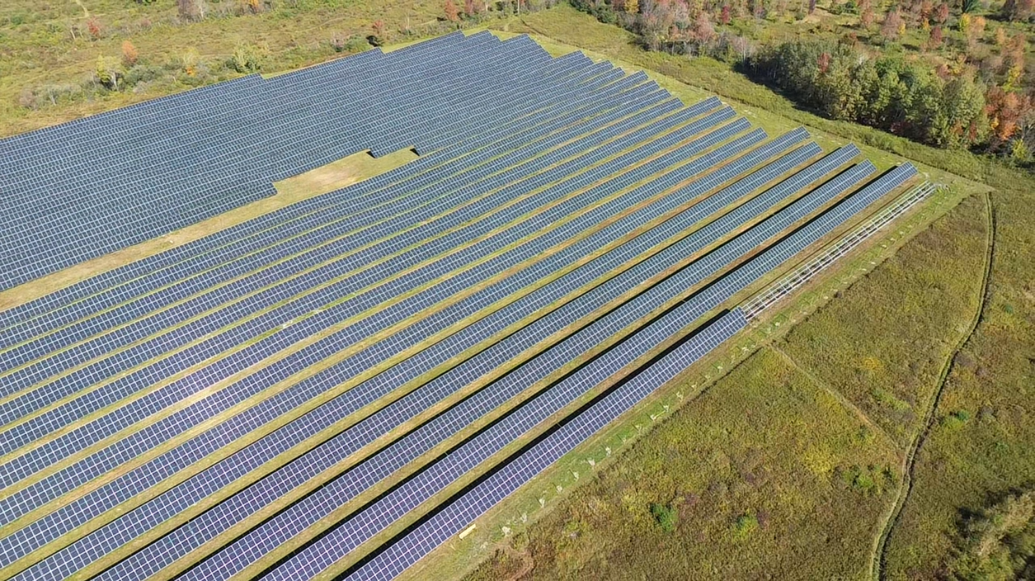 An aerial shot of solar arrays in a vast open field