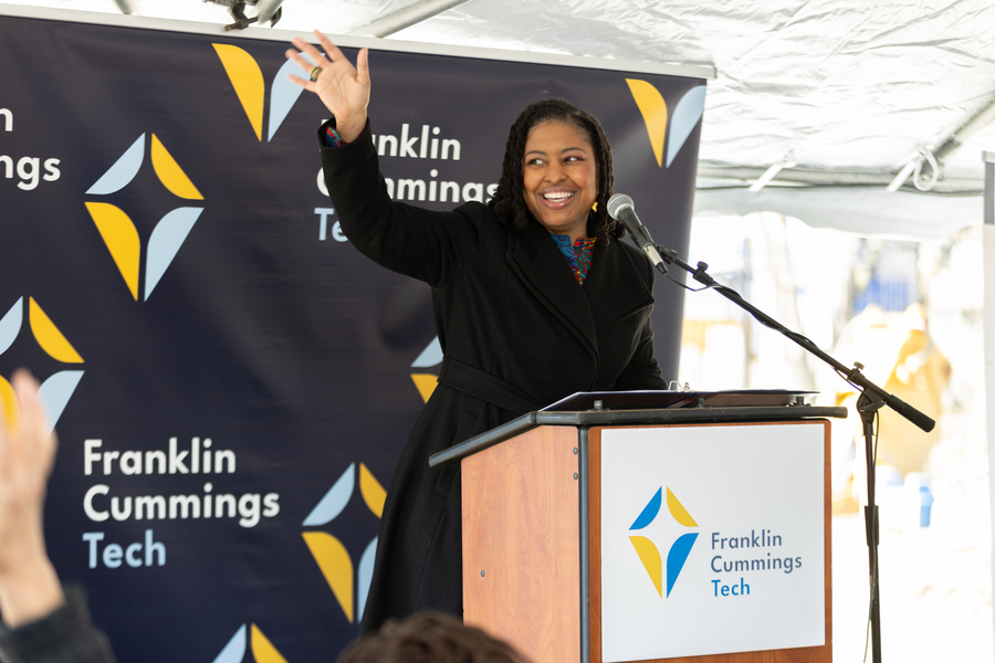 Franklin Cummings Tech’s President and CEO, Dr. Aisha Francis, stands behind a podium waving. 