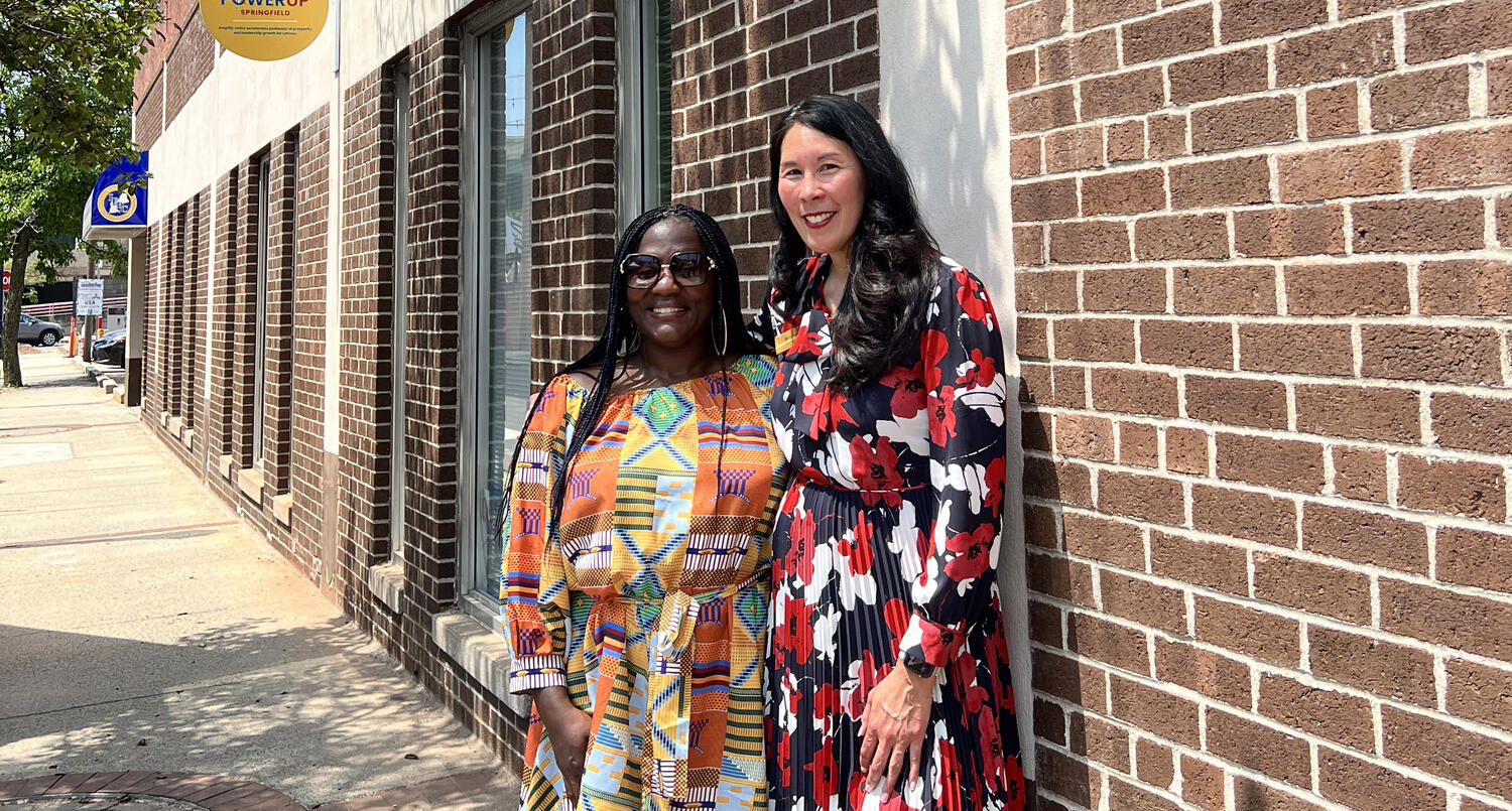 Two women standing in front of a brick building