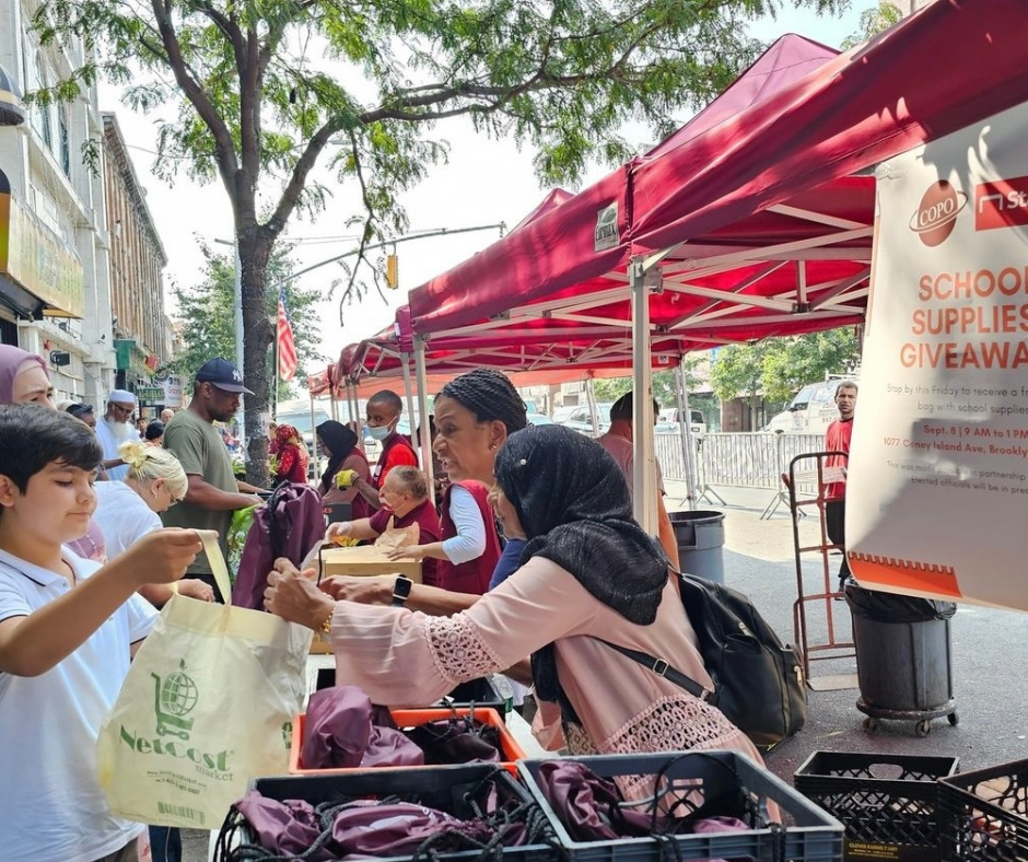 COPO staff and community members outdoors at a school supplies giveaway.