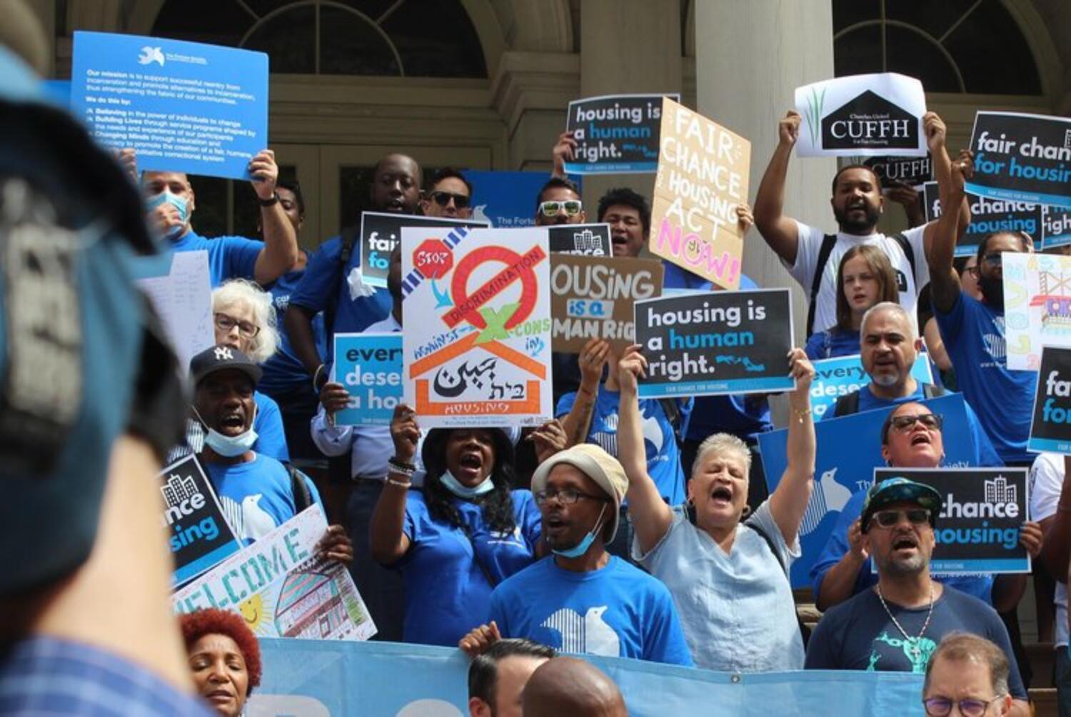 CUFFH members dressed in blue and holding signs, protest in front of NYC City Hall