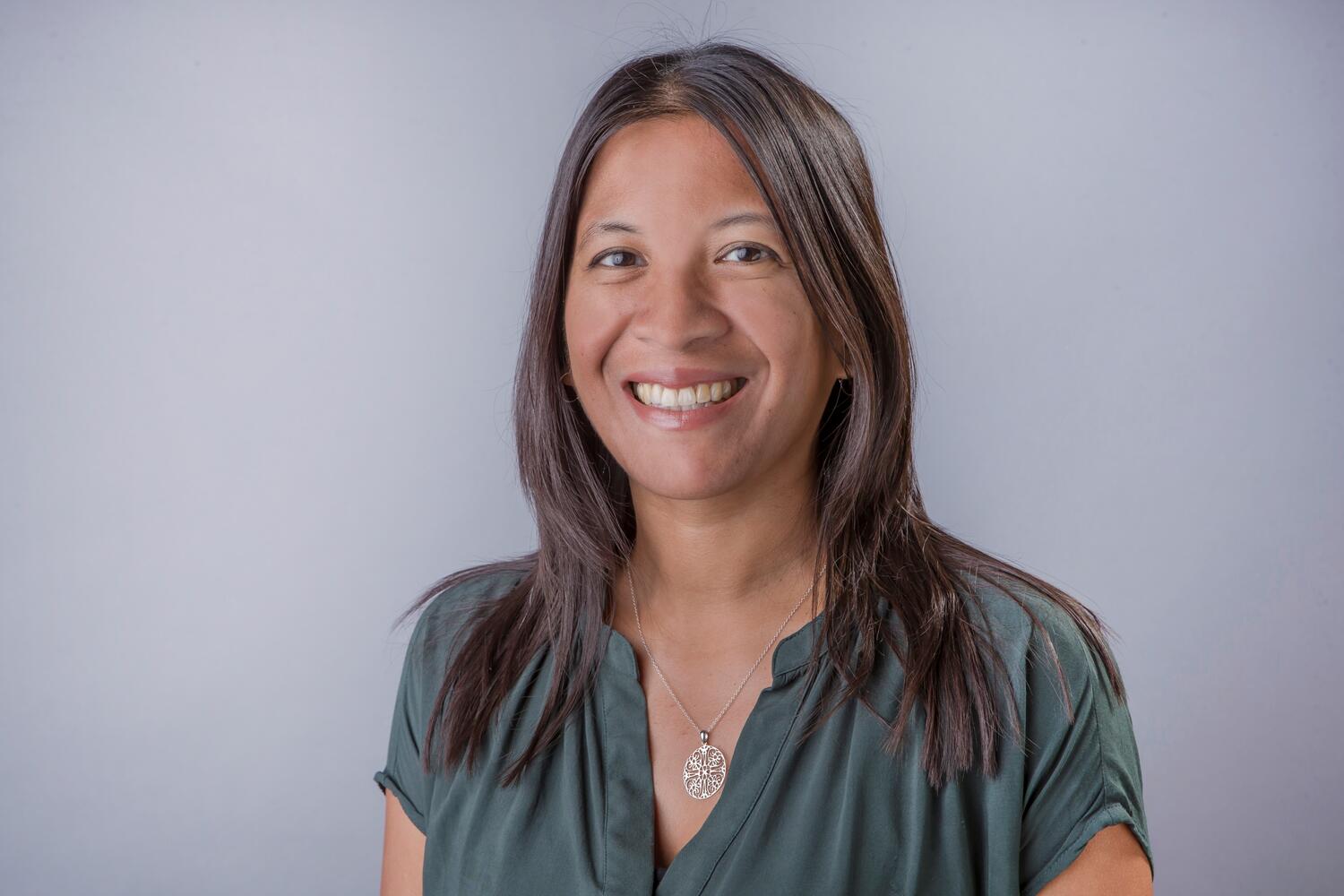 Headshot of Kristine Alvarez, smiling and wearing a dark green shirt