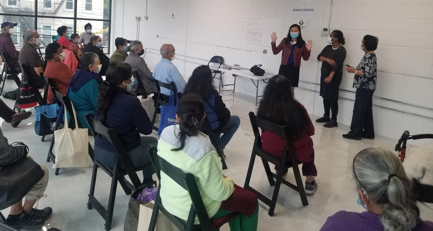 Dozens of people seated in chairs in a large room, looking at three people giving a presentation at the front. Photo provided by SACSS.