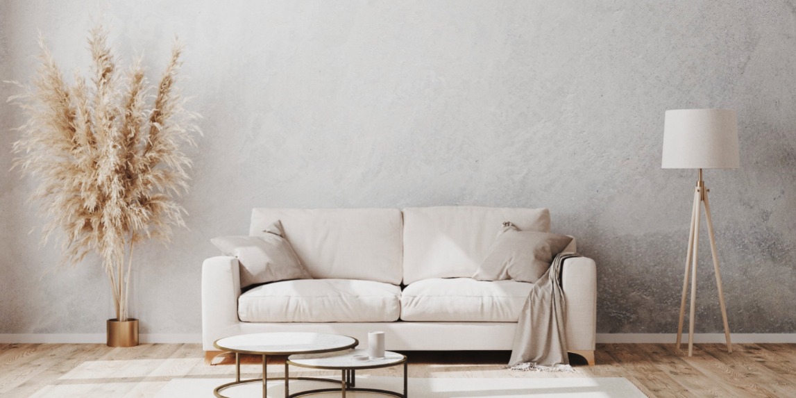 Stock image of a white couch in a brightly lit room with warm grey walls and light wooden floors