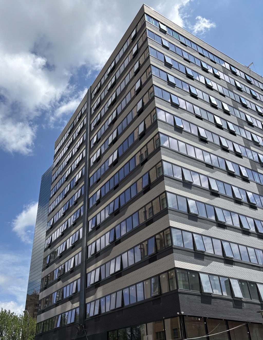 A tall building with windows reflecting a blue sky.