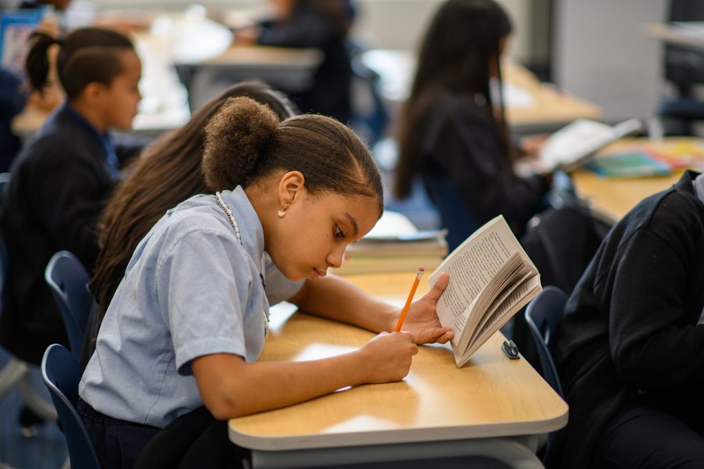 A Bold student writes at their desk.
