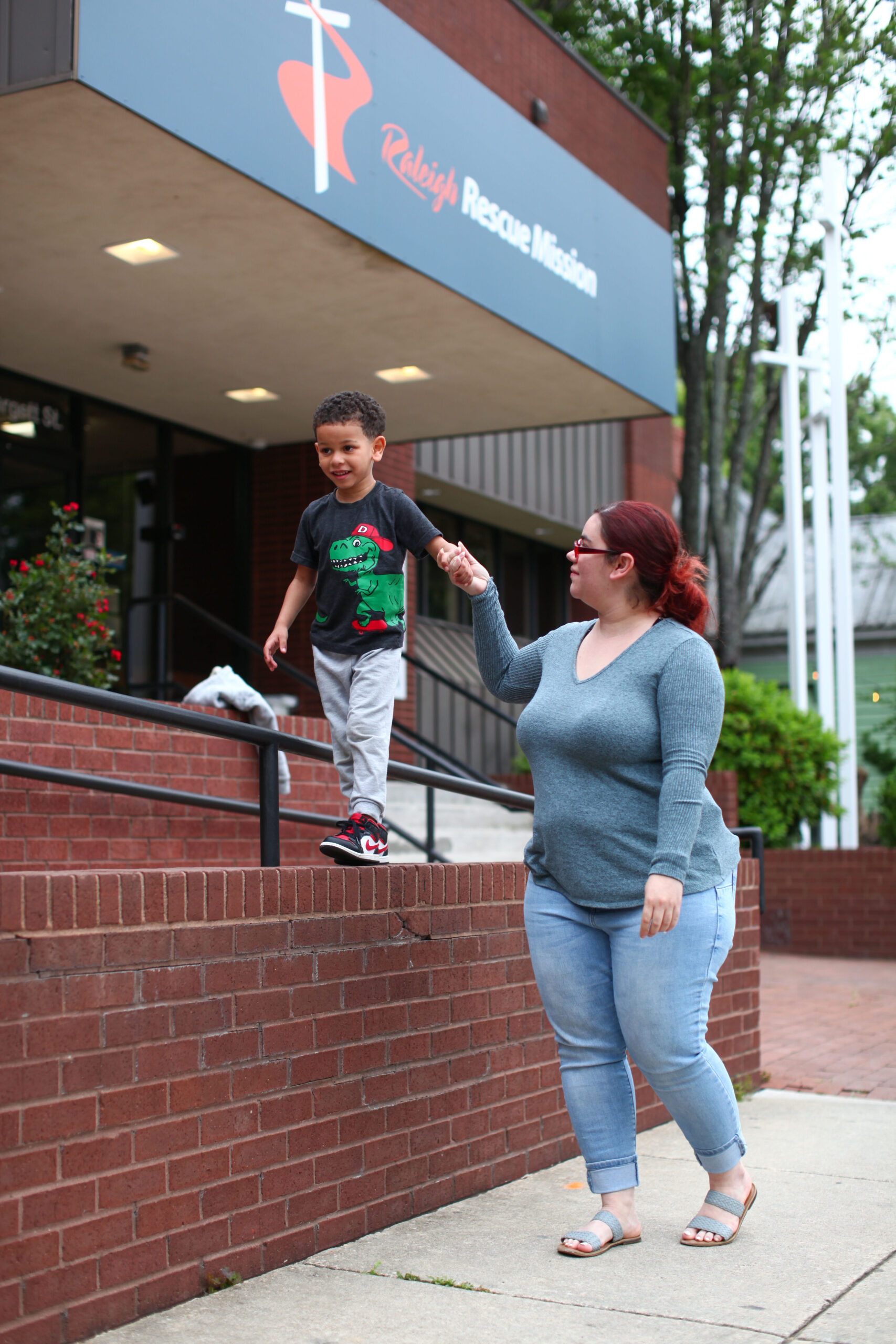 A mother and her son play in front of Raleigh Rescue Mission's headquarters.