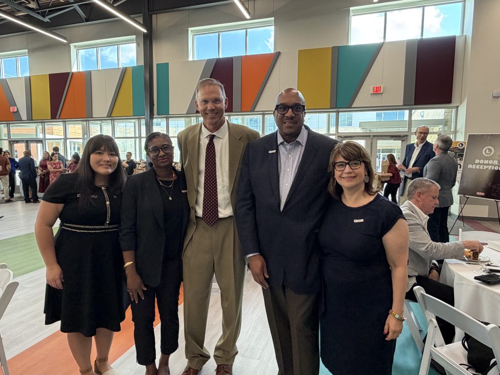 Five people smiling for the camera in a large brightly colored room.