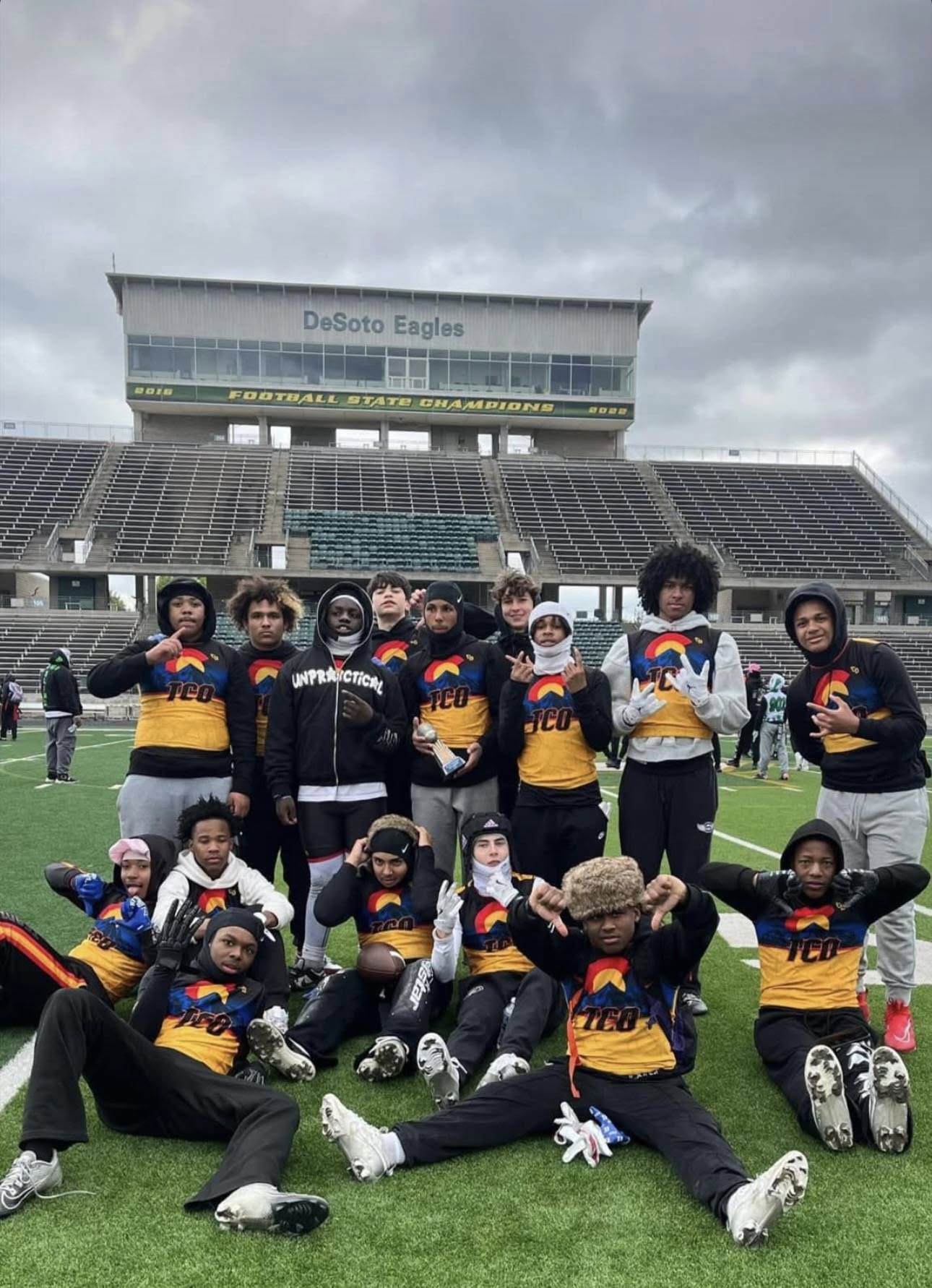 A group of Athletics & Beyond student athlete smile for a photo at a football stadium