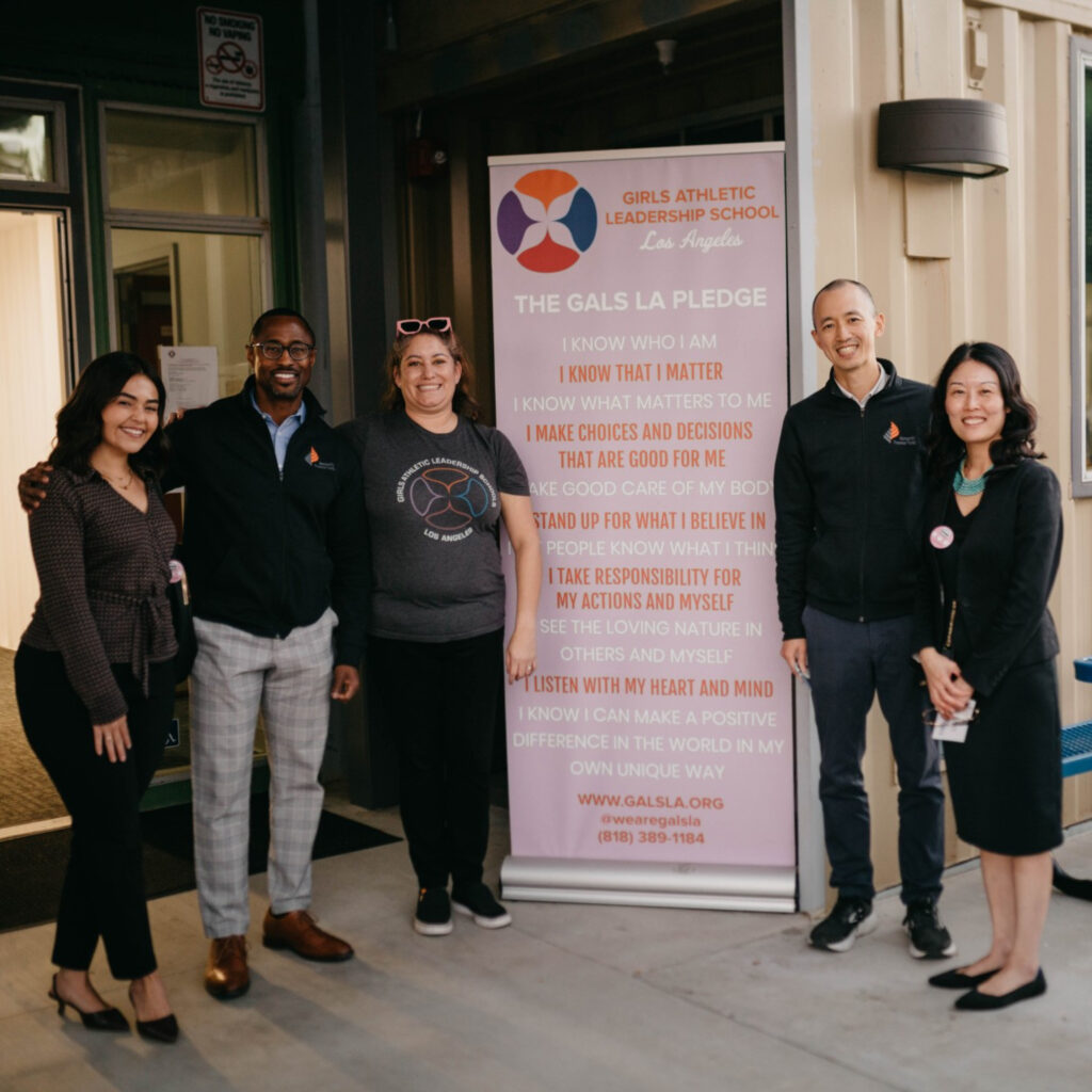 Diverse people smiling in front of a sign