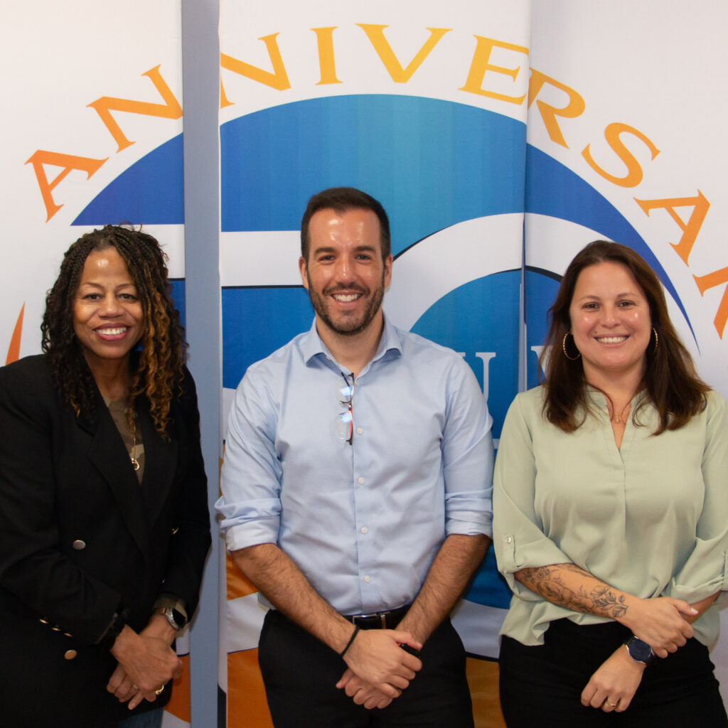 A diverse group of people smiling in front of a sign